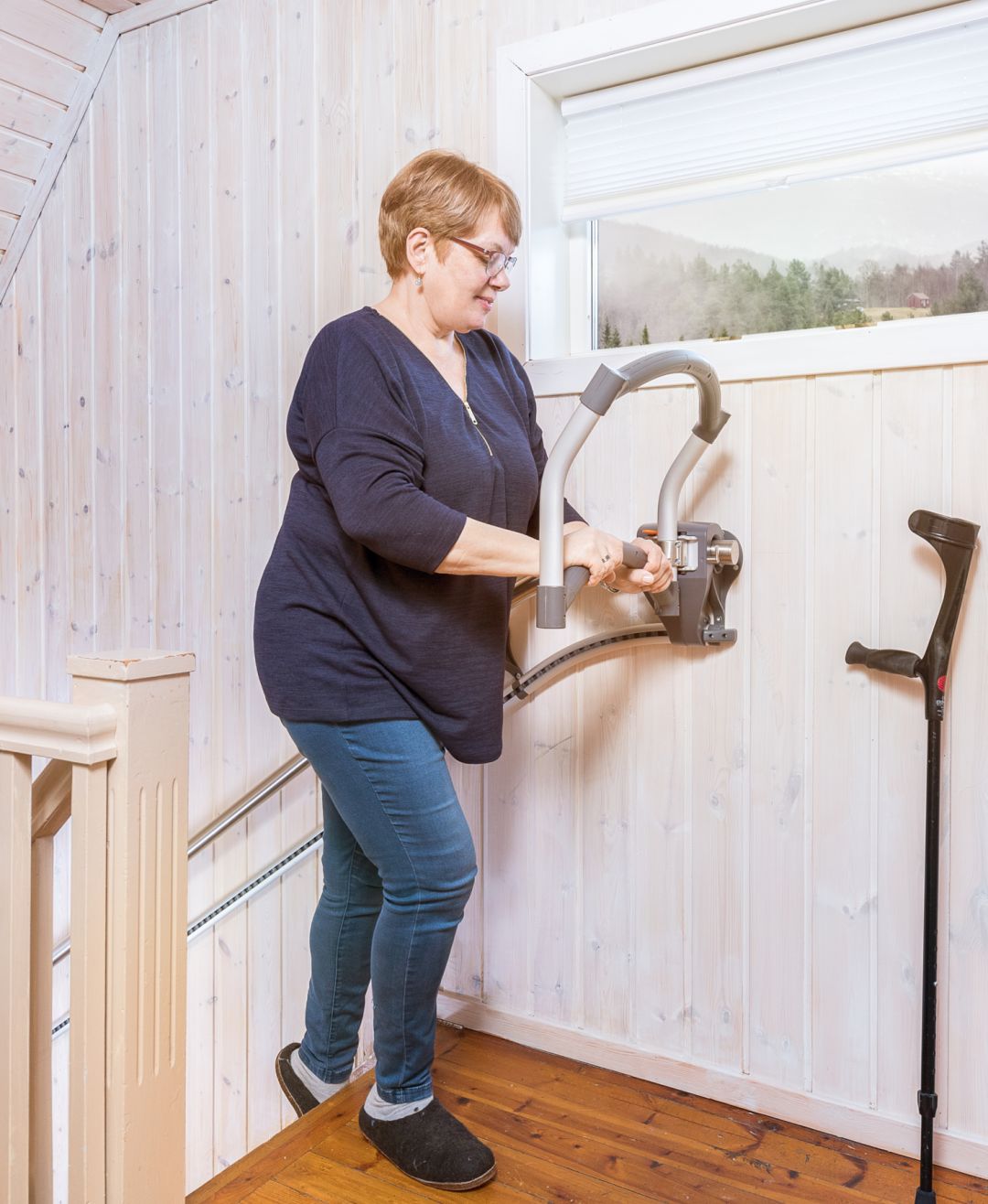 De foto toont een vrouw die de trap op loopt met de AssiStep traphulp
